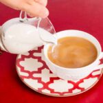 Coffee cup with person adding creamer